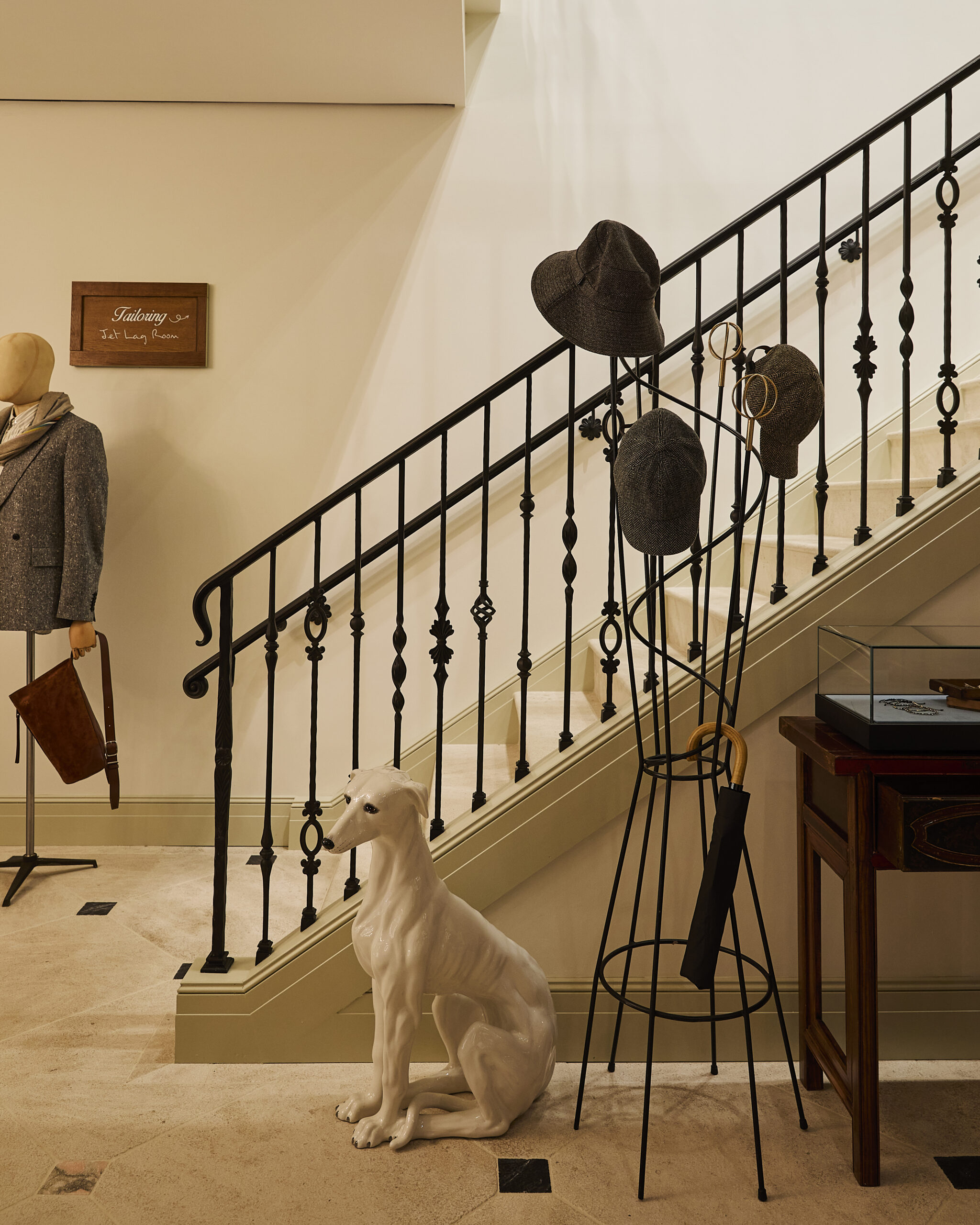 Staircase with a tailoring sign, hat stand and ceramic dog at Paul Smith Madison Avenue