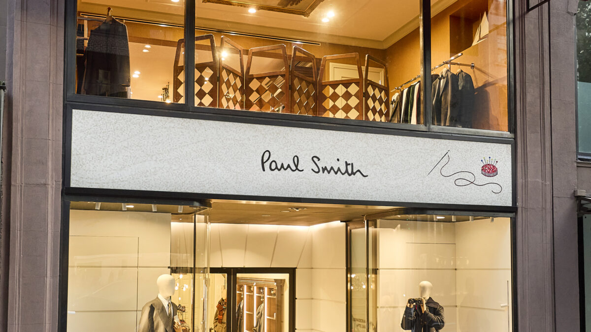 Exterior of Paul Smith’s two-storey Madison Avenue flagship with a red awning and illuminated shop windows