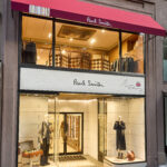 Exterior of Paul Smith’s two-storey Madison Avenue flagship with a red awning and illuminated shop windows