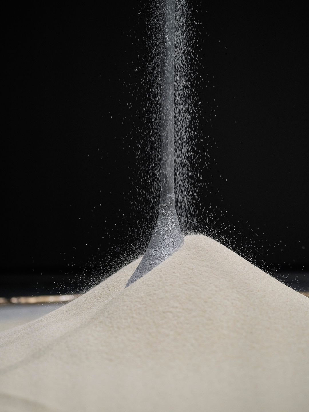 Sand falling into a conical mound in the exhibition installation