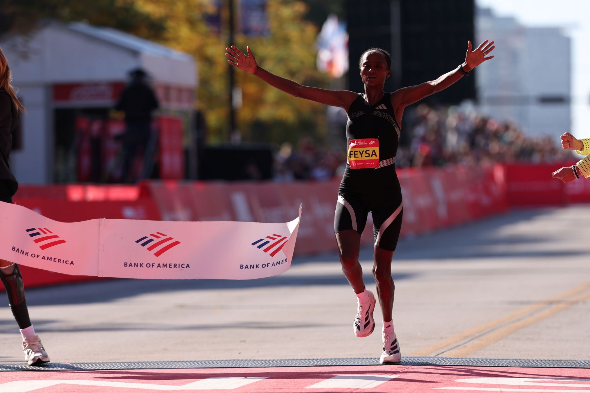 Runner crossing the Chicago Marathon finish line in adidas racing footwear