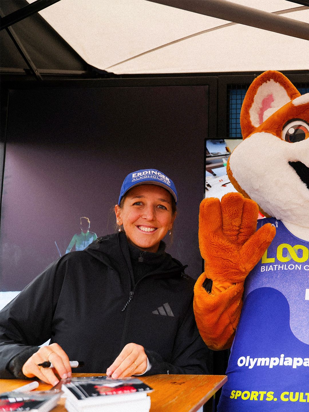 Athlete signing memorabilia beside the Loop One mascot