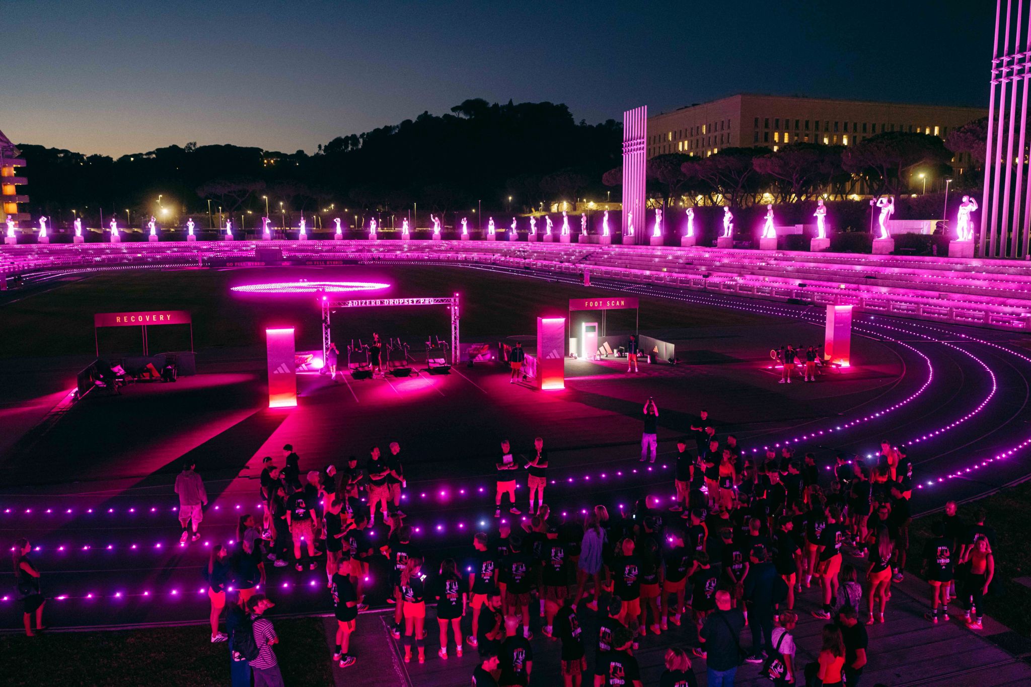 Participants gather inside adidas’s pink-lit Hybrid Hub at Stadio dei Marmi