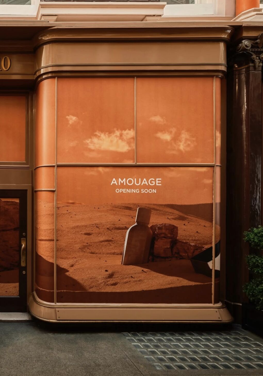 Amouage window graphic with a fragrance bottle and the words Opening Soon