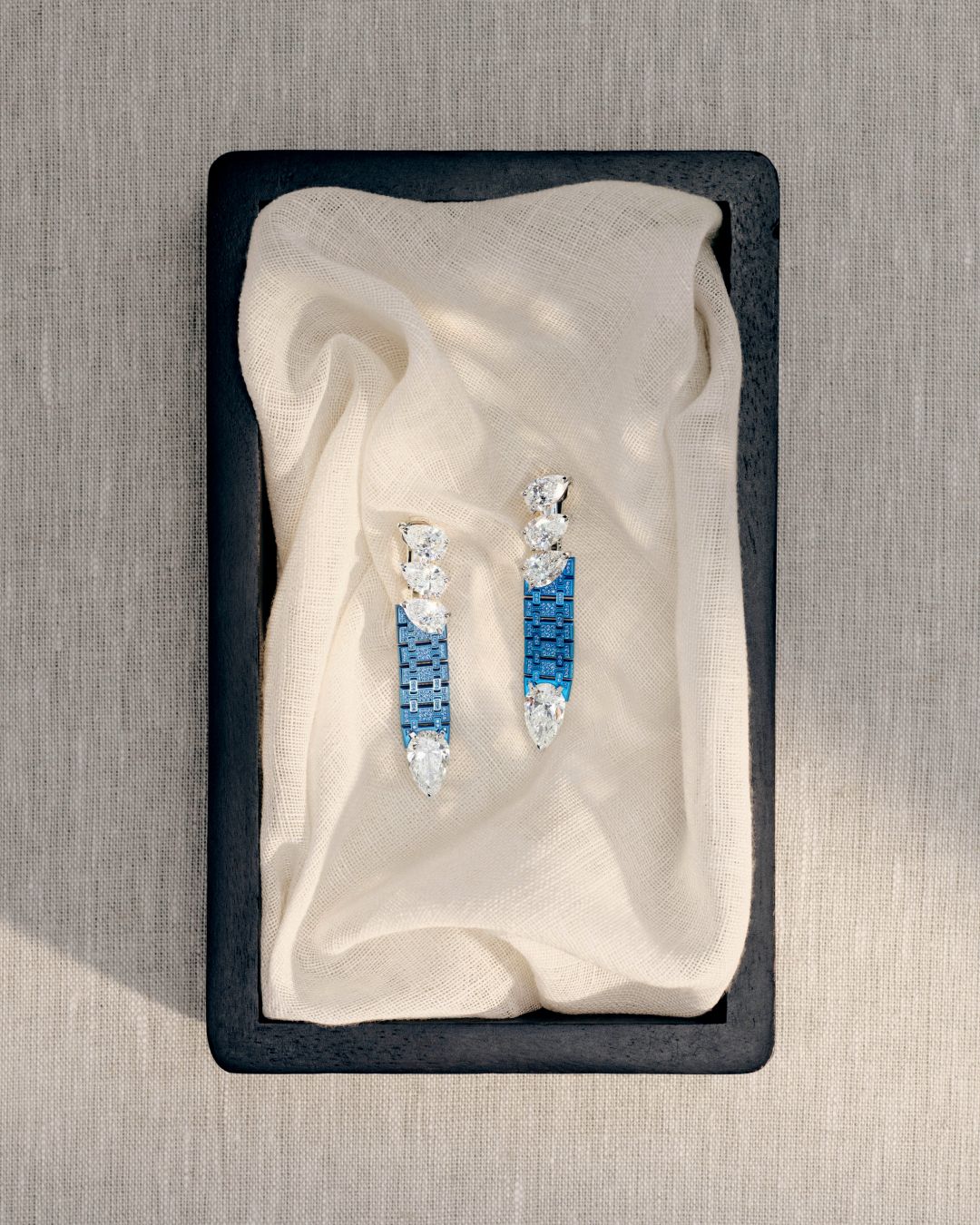 Blue and diamond Dream of Joux earrings displayed on fabric