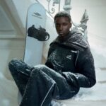 Model in Balenciaga black skiwear holding a snowboard