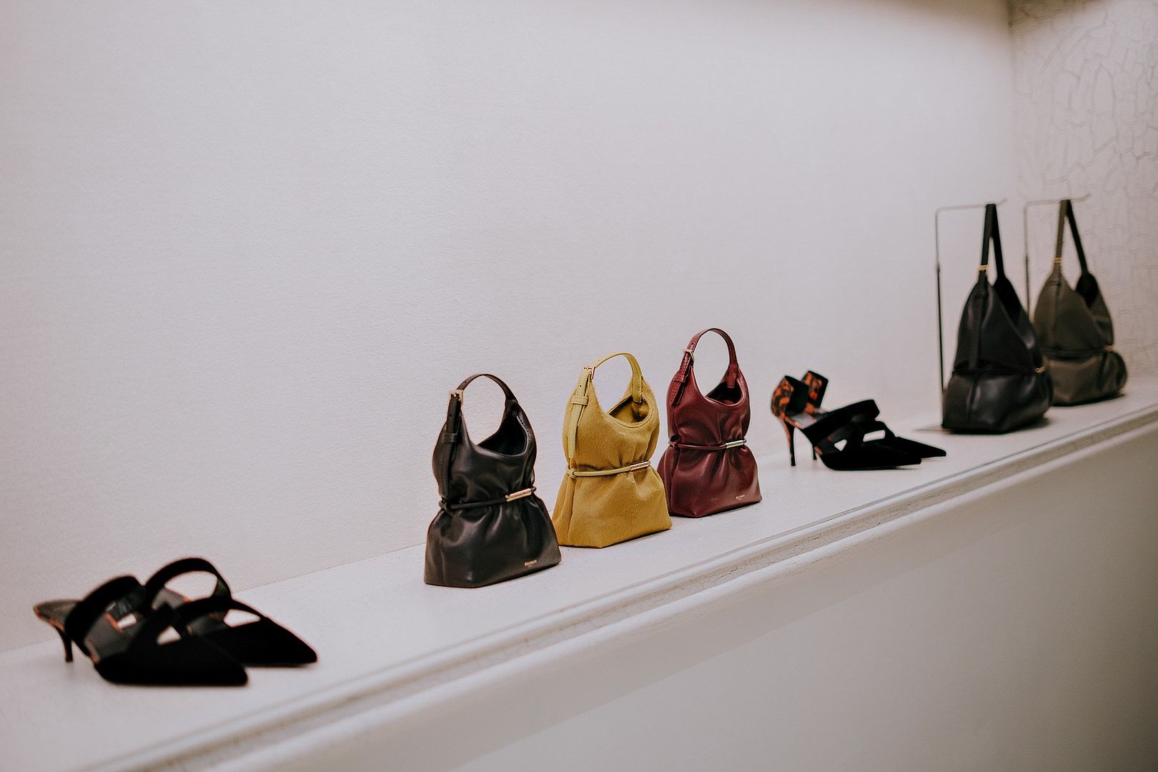 Balmain handbags and shoes arranged on a display shelf in the Milan flagship