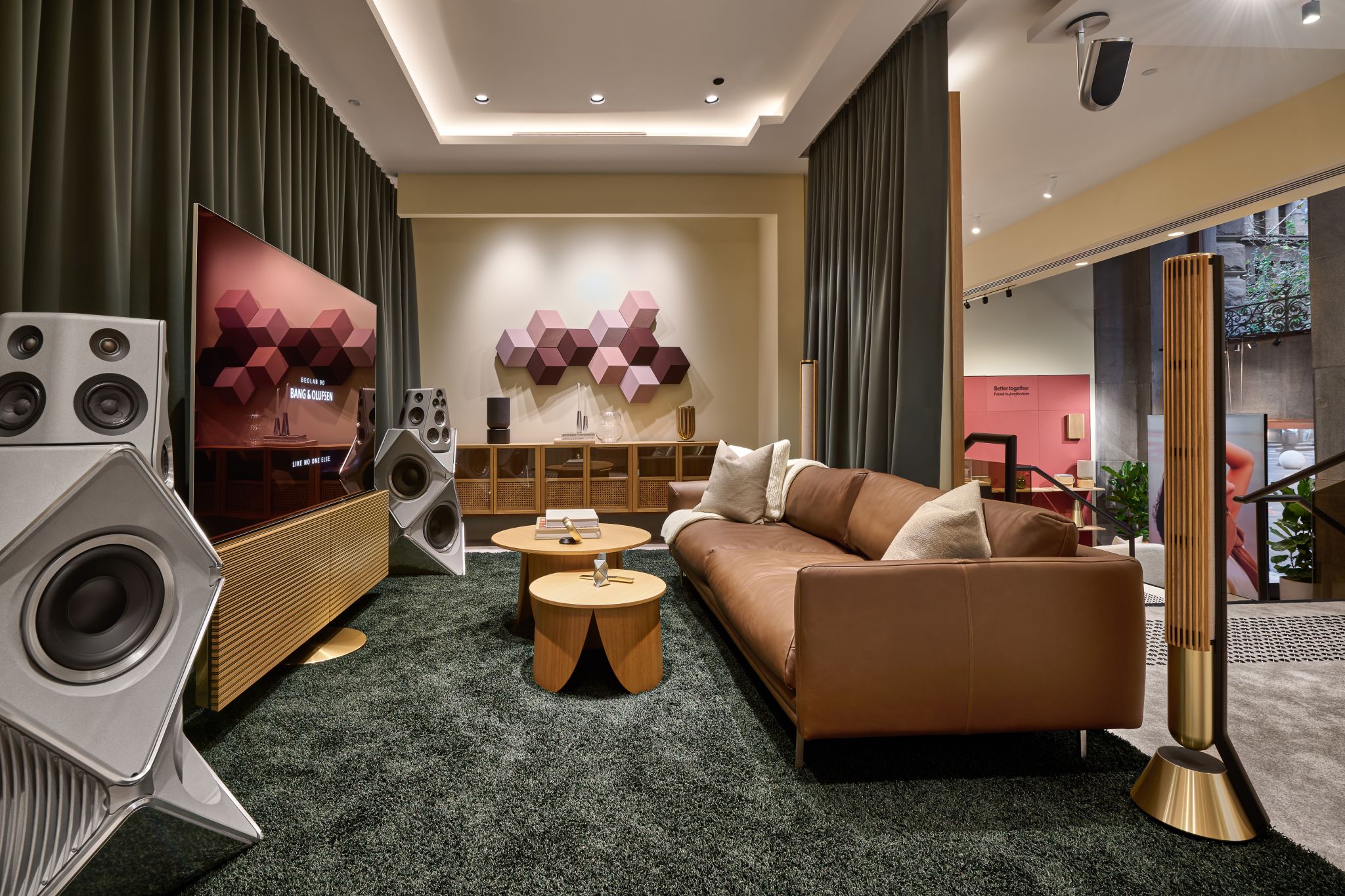 Speakers and seating in a green-carpeted Bang & Olufsen display room