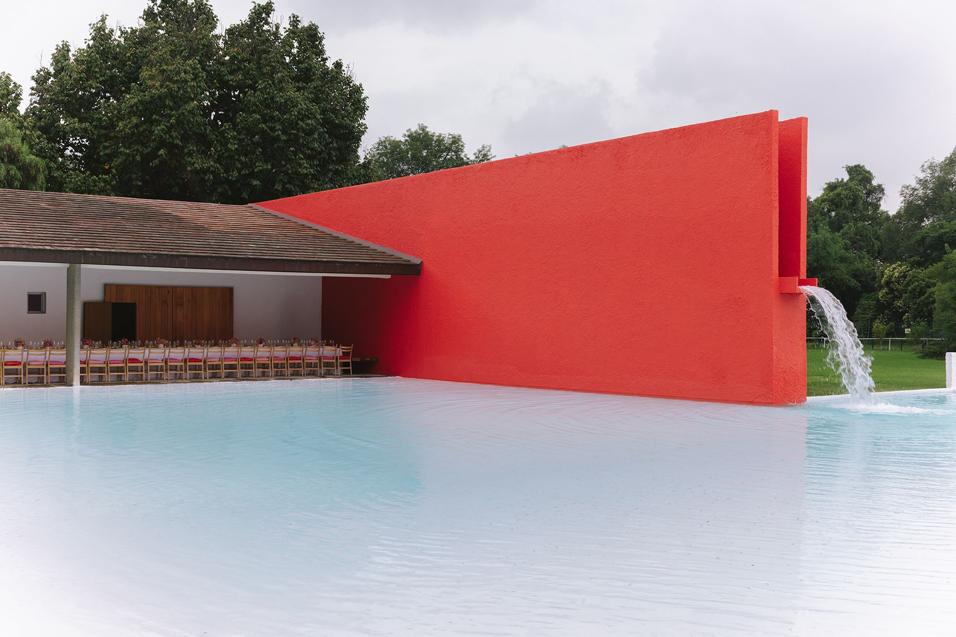 Red architectural wall reflected in a pool at the event setting