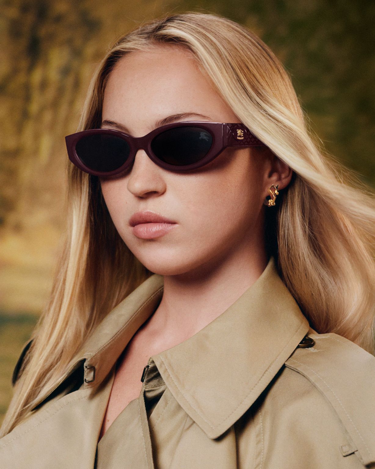 Lila Moss wearing burgundy Burberry sunglasses and a beige trench coat in the Autumn Winter 2026 eyewear campaign
