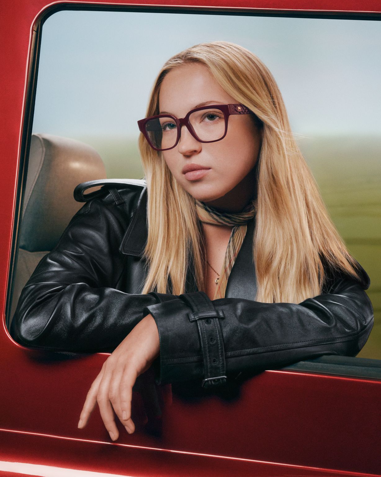 Lila Moss wearing burgundy Burberry optical frames beside a red car