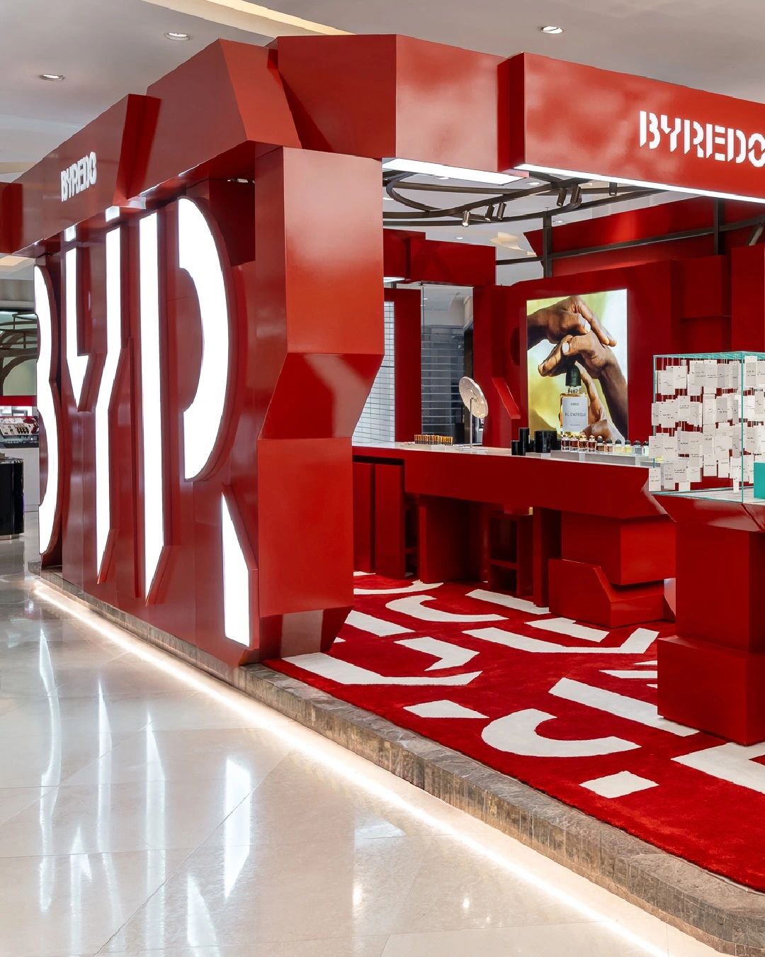 Red Byredo retail installation with fragrance displays, photograph 2
