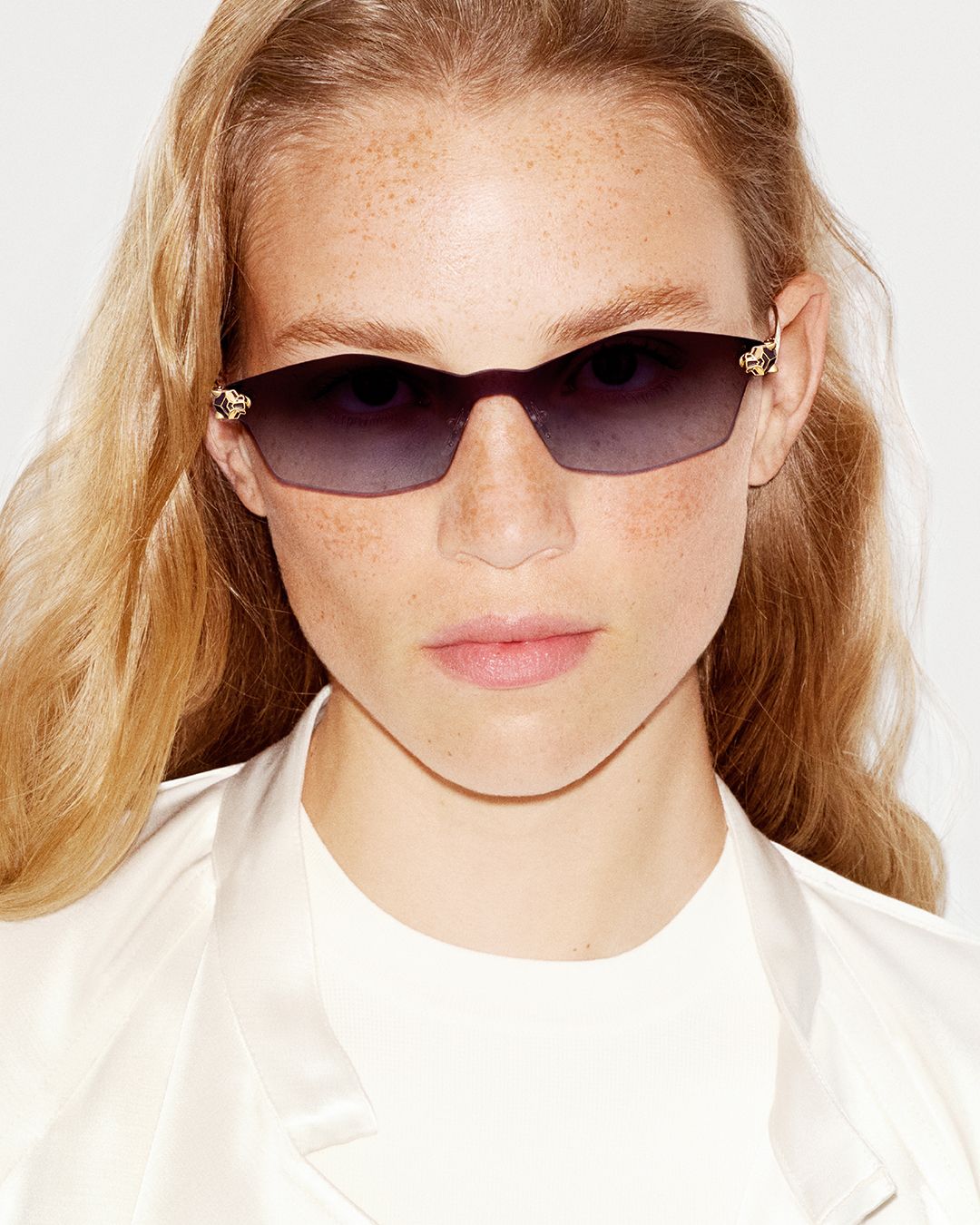 Model wears tinted Cartier eyewear with panther-head accents at the hinges