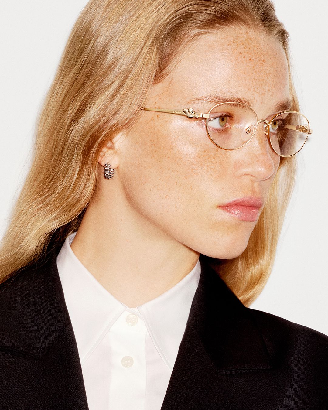 Model wears round clear-lens Cartier eyewear with gold-tone detailing