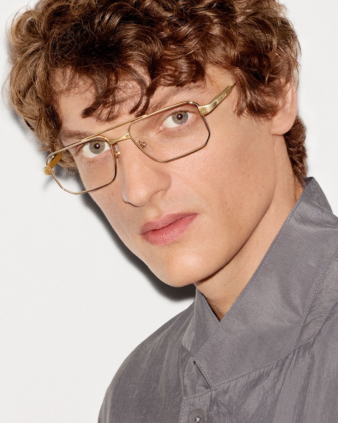 Model wears rectangular clear-lens Cartier eyewear with a gold-tone frame