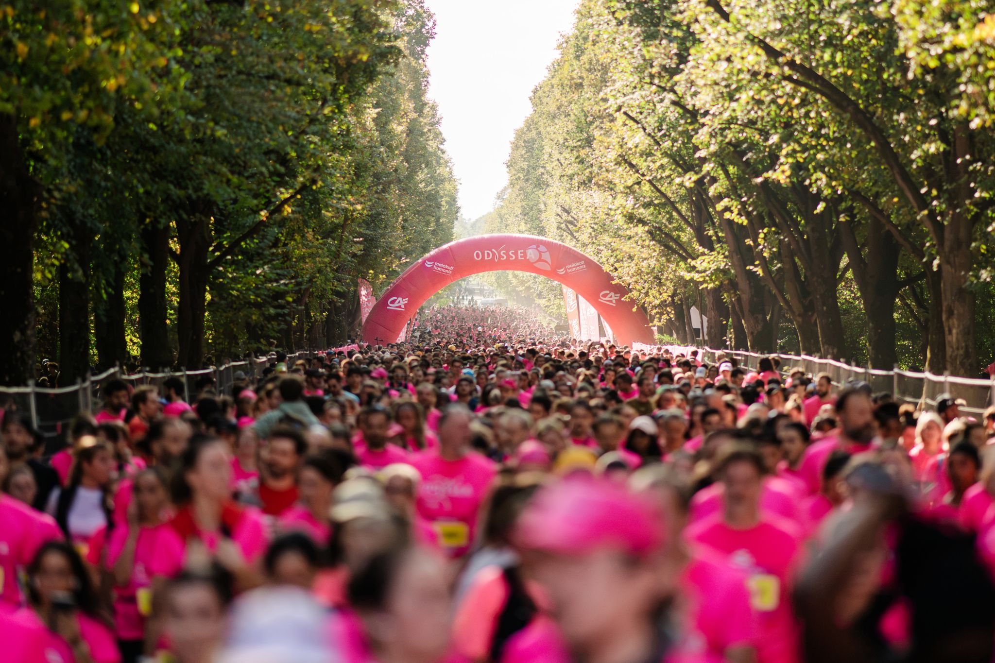 Participants in pink gather at the Odysséa Paris starting arch