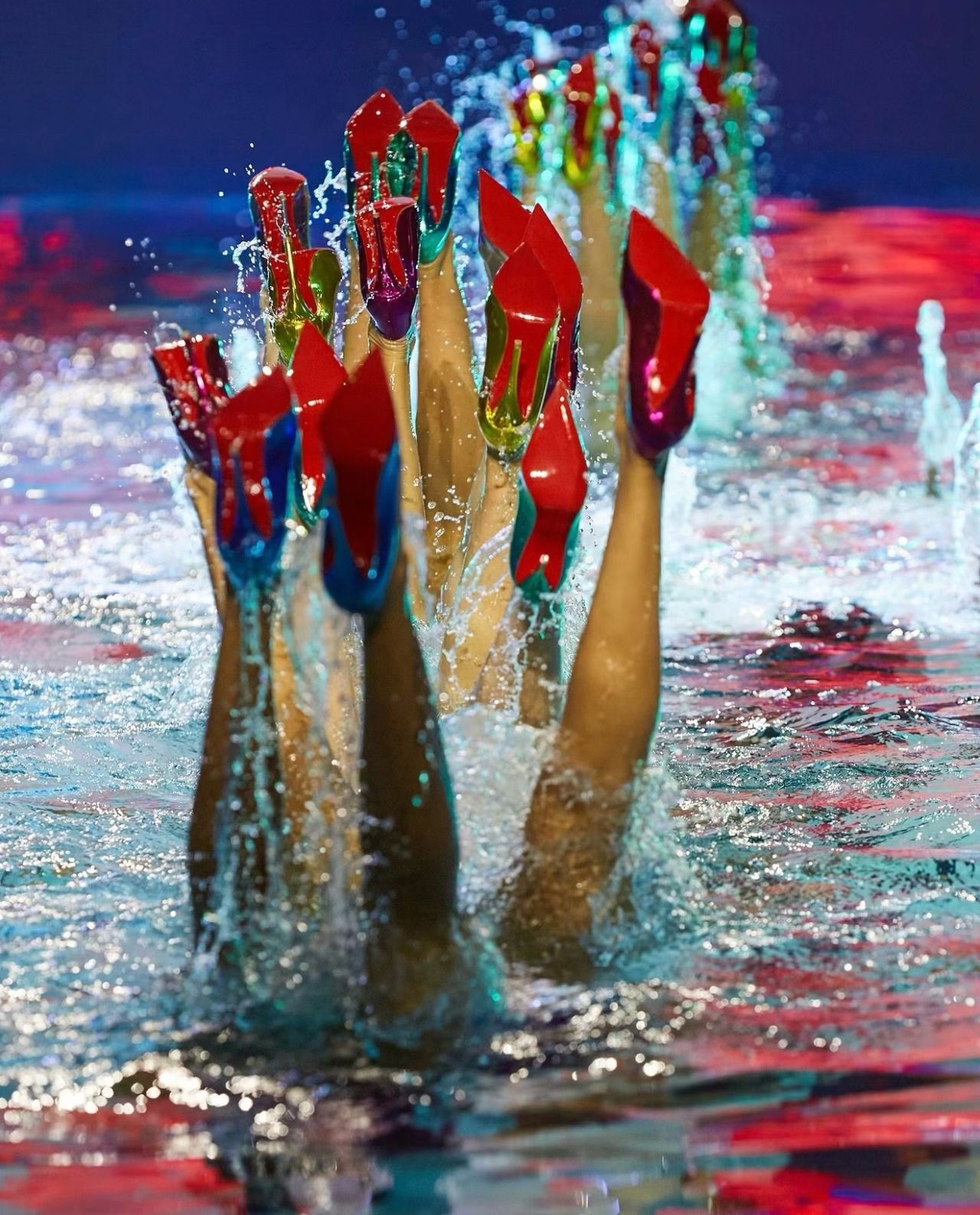 Archival 2024 artistic swimmers hold red-soled shoes above the pool