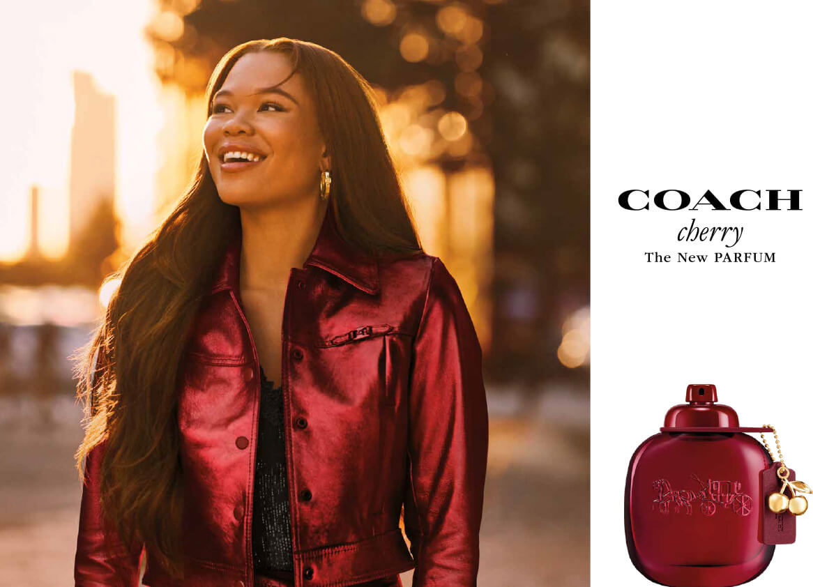 Storm Reid smiling beside Coach Cherry fragrance imagery in the 2026 campaign.