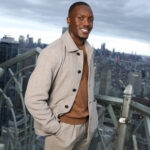 Letsile Tebogo in a light jacket with a city skyline behind him