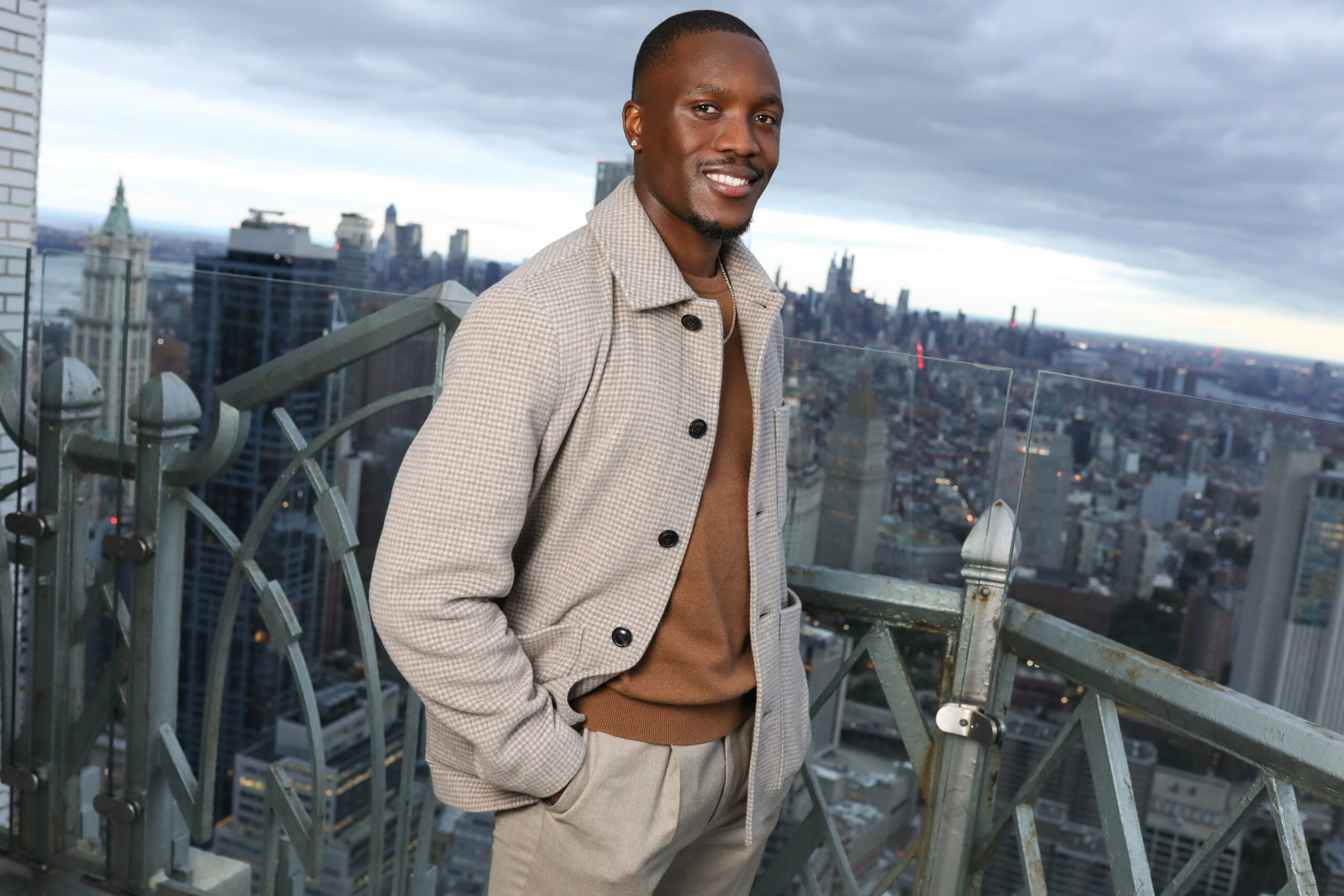 Letsile Tebogo in a light jacket with a city skyline behind him