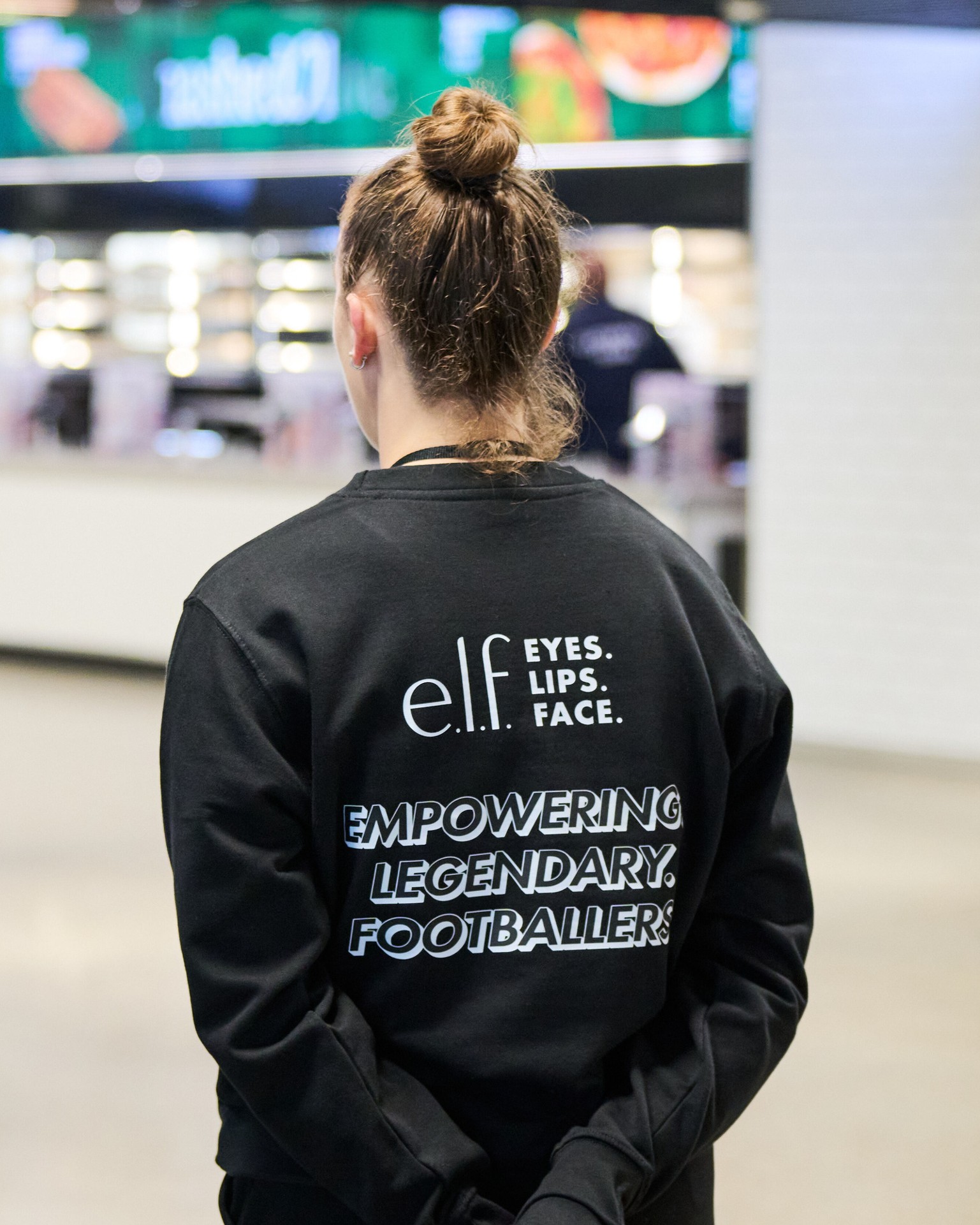Event representative wearing a jacket branded with e.l.f. and women’s football messaging