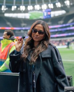 Attendee holding an e.l.f. product beside the football pitch