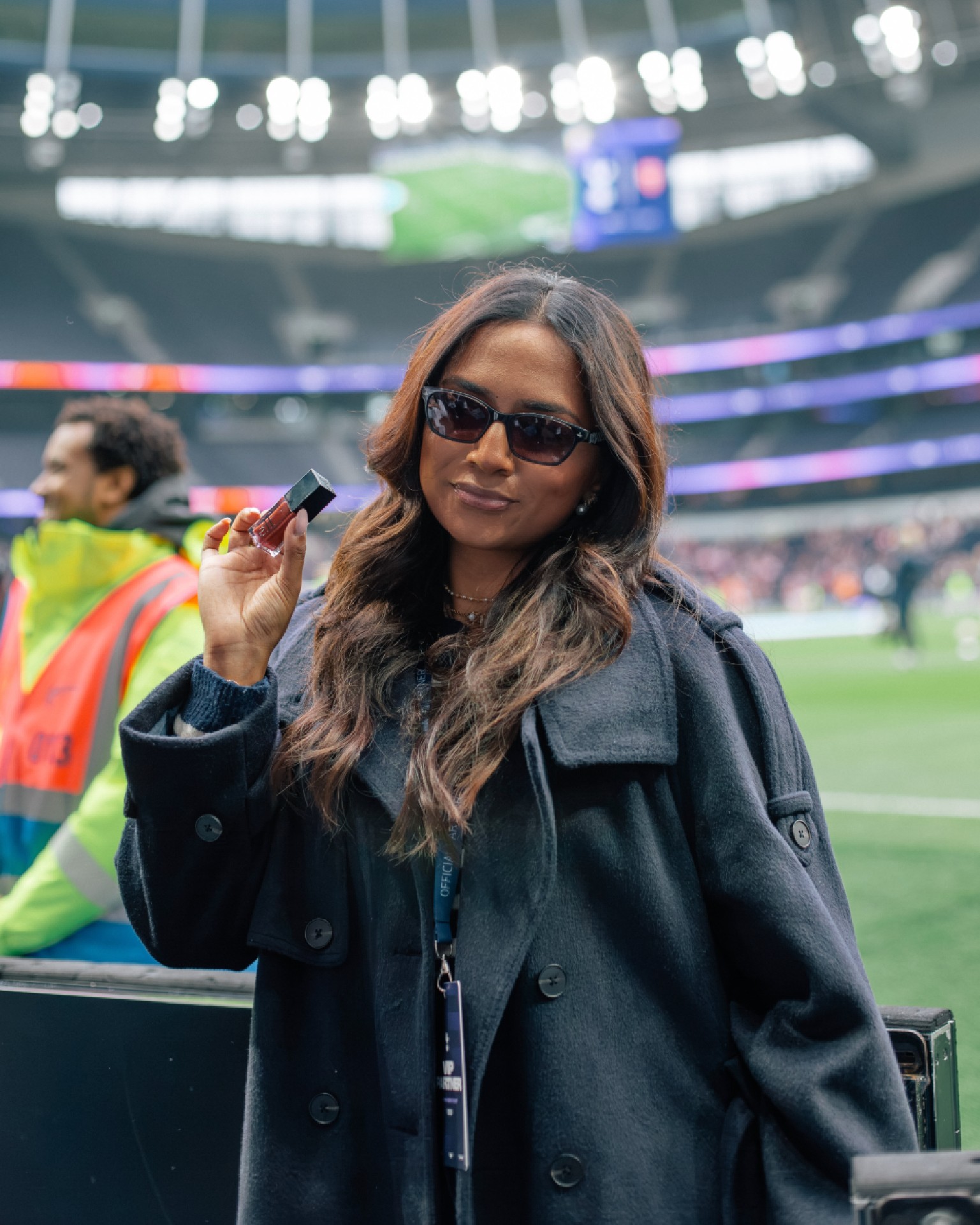 Attendee holding an e.l.f. product beside the football pitch