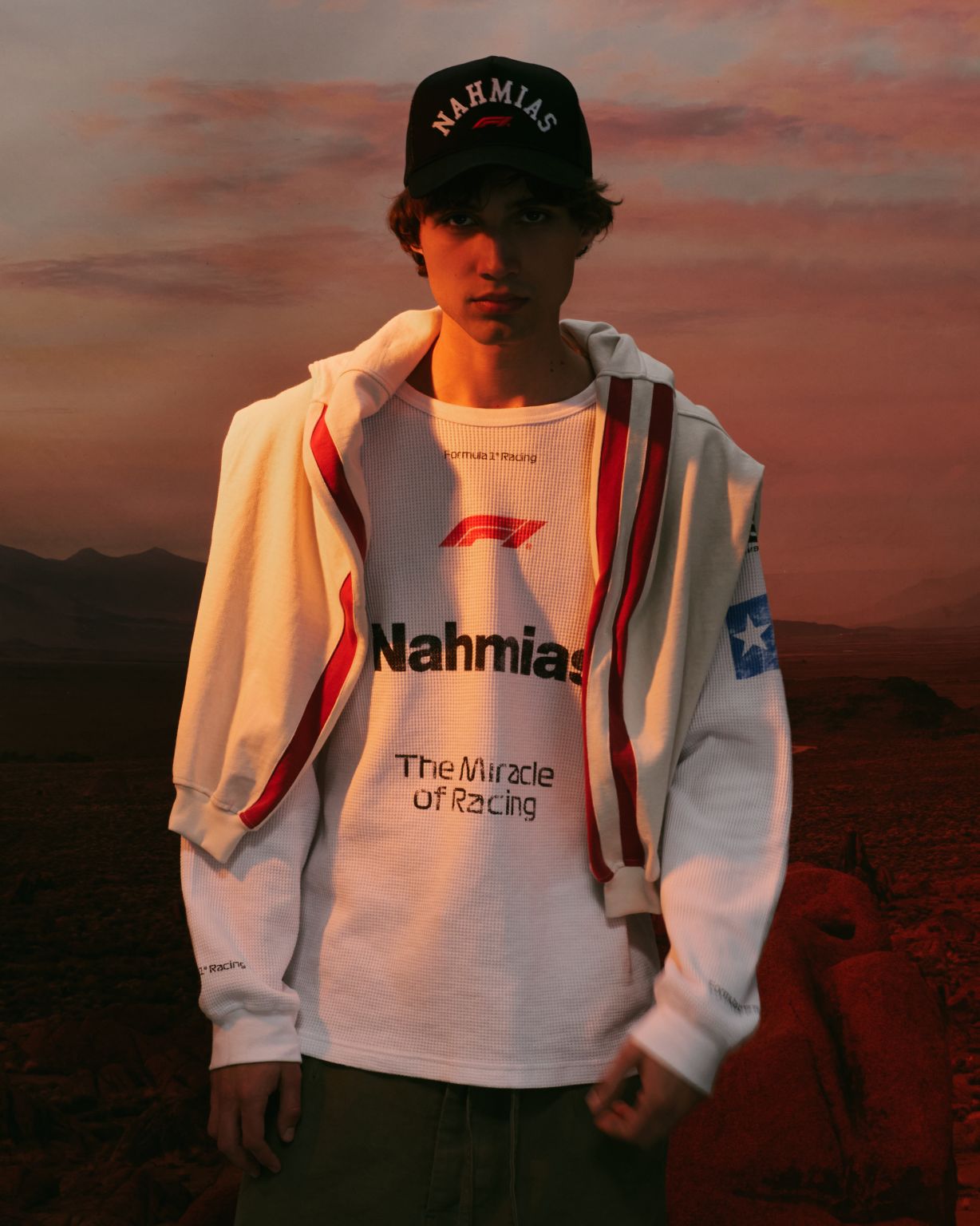 Model wearing a cream jacket, graphic top and NAHMIAS cap from the Formula 1 Austin collection