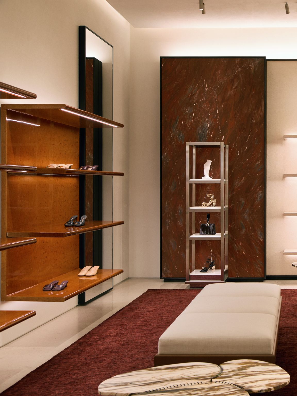 Footwear shelving beside a red accent wall and seating