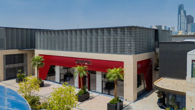 Exterior of Ferrari's Riyadh showroom with red facade and palm trees