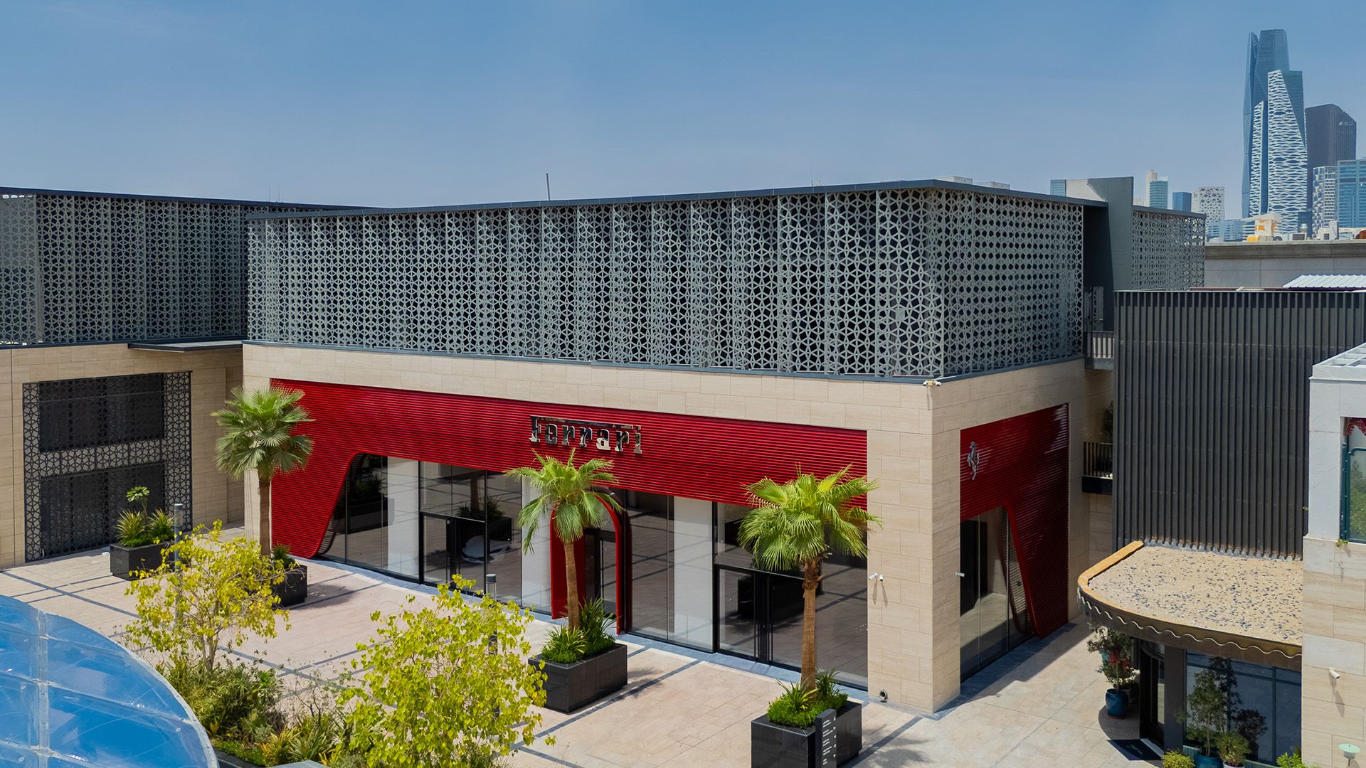 Exterior of Ferrari's Riyadh showroom with red facade and palm trees