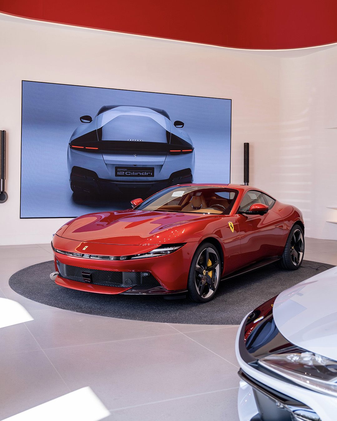 Red Ferrari displayed before a digital screen in the Riyadh showroom