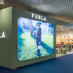 Exterior of Furla’s exhibition stand at TFWA 2026 in Cannes, with an illuminated campaign display