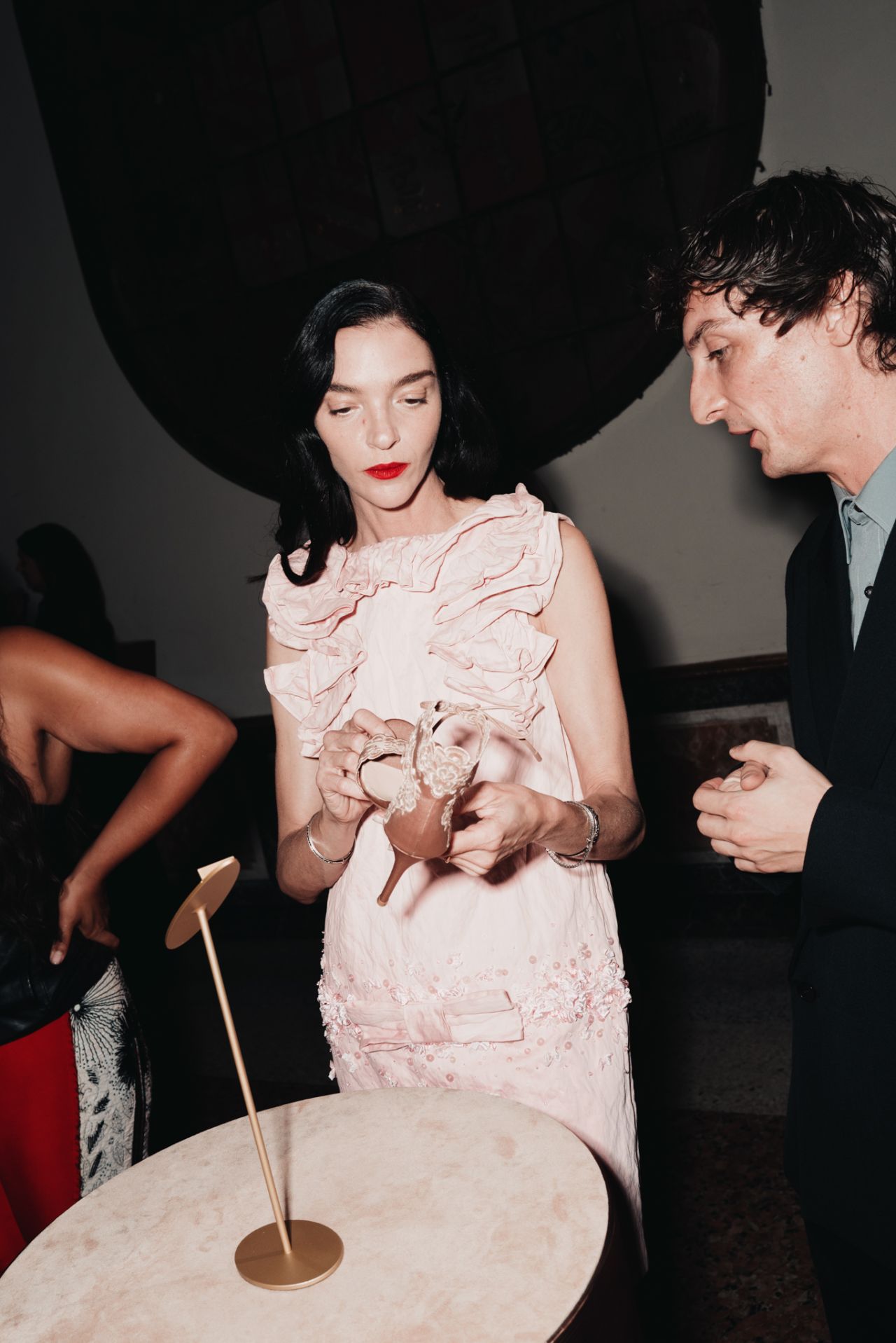 Guest examines an embellished Gianvito Rossi shoe at the event