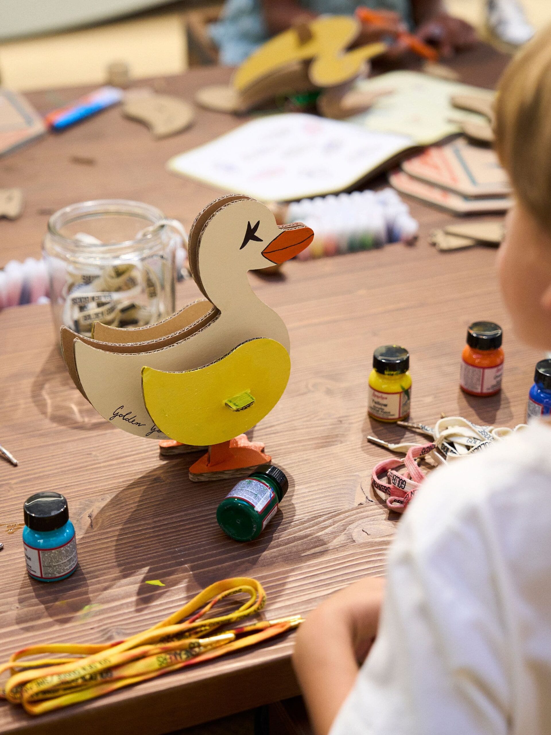 A cardboard Goldy mascot being painted at a Golden Goose Kids workshop