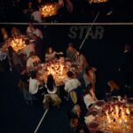 Guests seated around candlelit dining tables on the padel courts at Golden Goose Wild Stars in Milan.