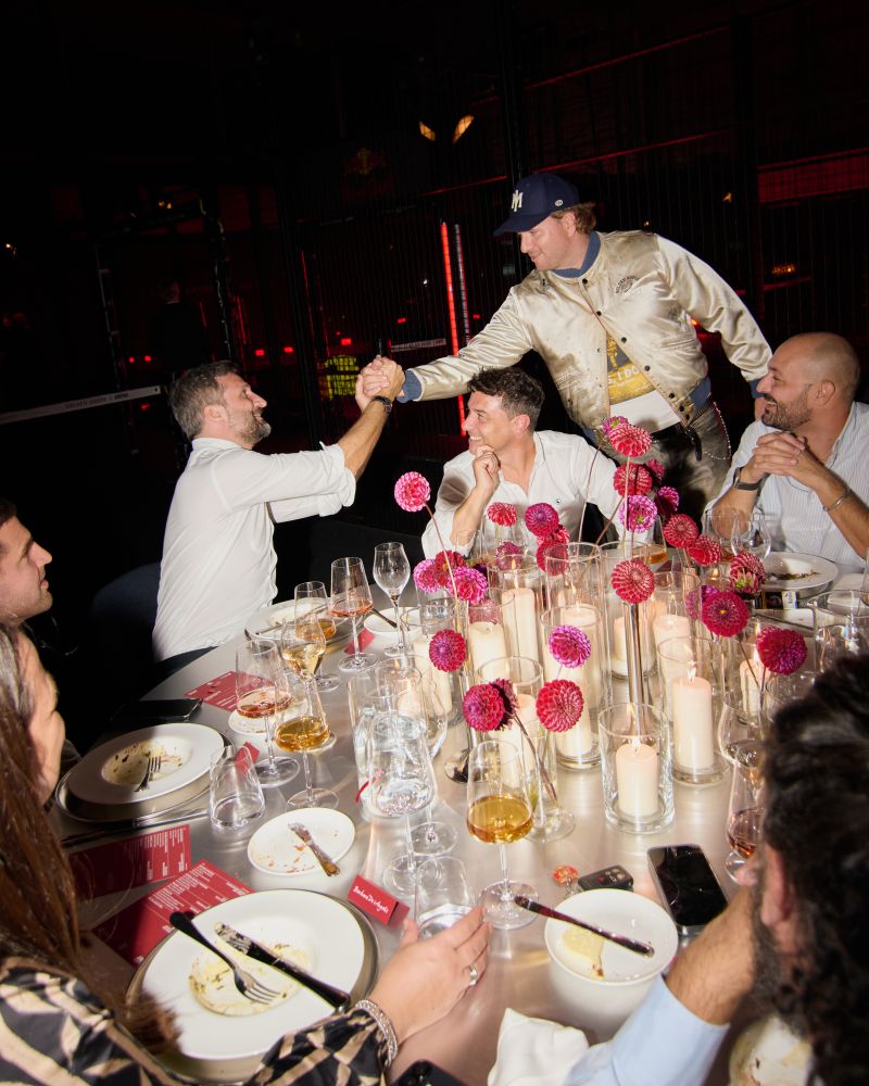 Guests greeting each other at a candlelit dinner table during Golden Goose Wild Stars in Milan.