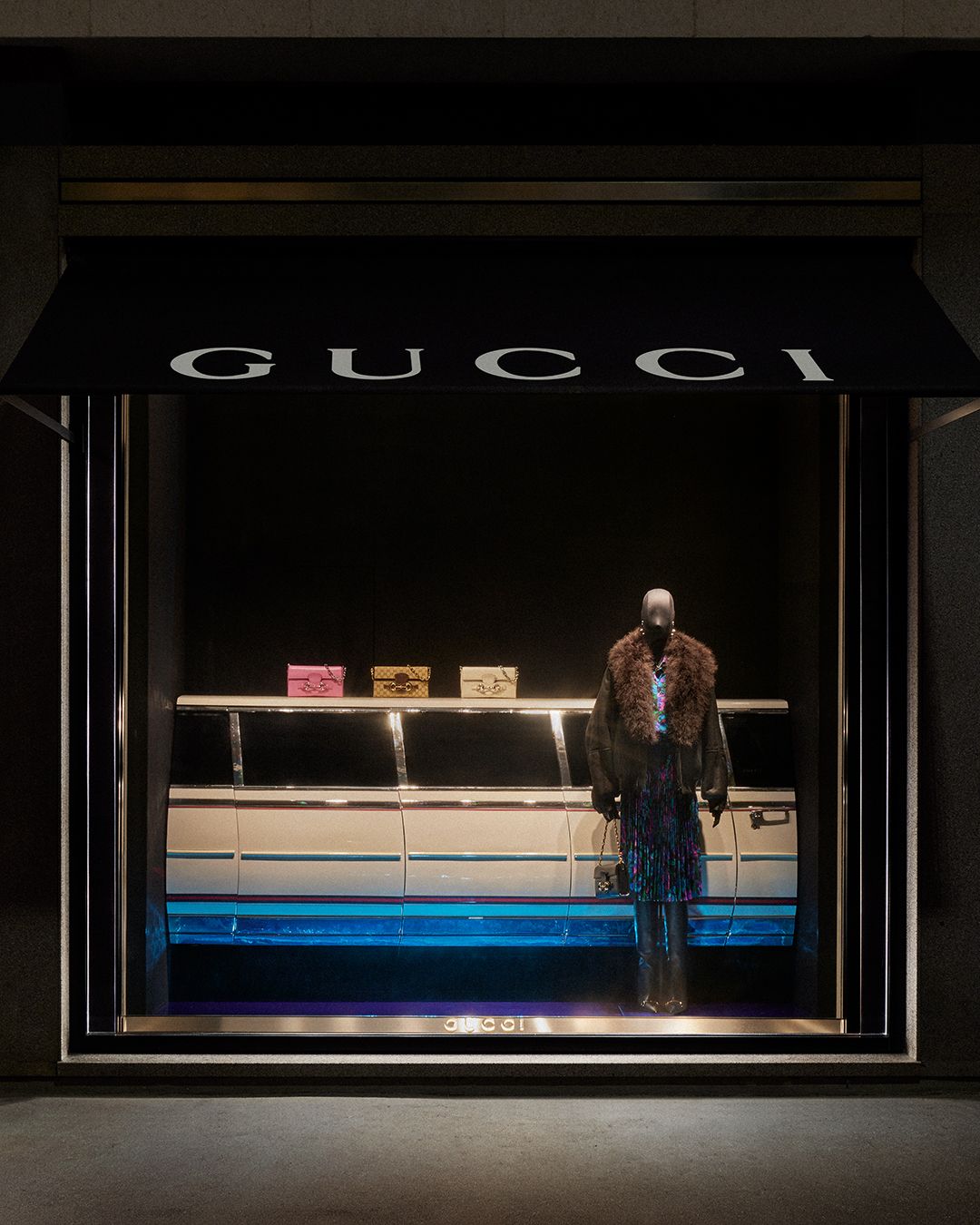 Gucci window with a mannequin and a long vehicle backdrop