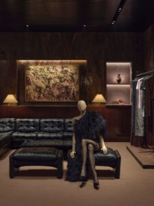 Mannequin and clothing display beside dark leather seating inside Gucci’s Paris flagship