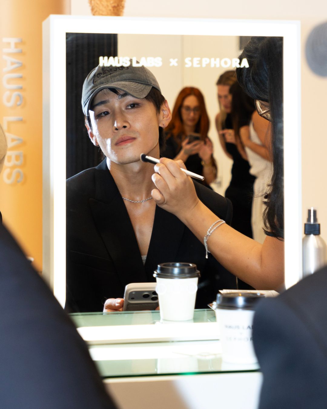 An artist demonstrating complexion makeup at a Haus Labs mirror