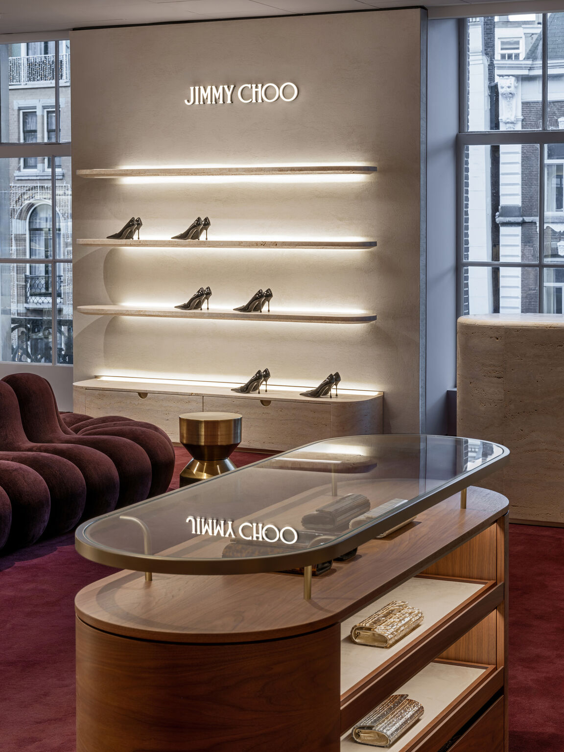 Illuminated shoe shelves and a glass-topped display at Jimmy Choo de Bijenkorf Amsterdam