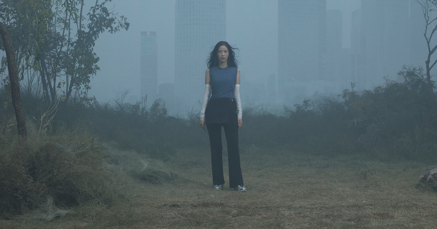 JISOO stands between urban buildings and grassland in Salomon's IN THE OPEN campaign