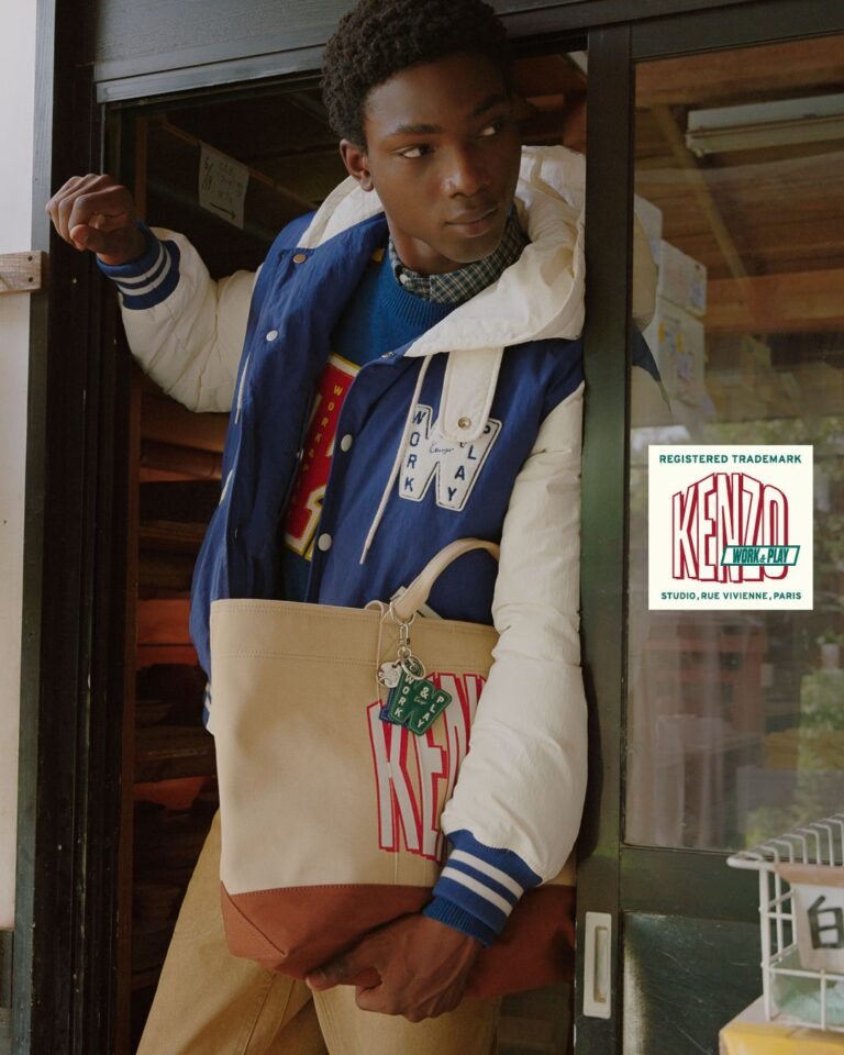 Model wears a KENZO Work and Play varsity jacket and carries a graphic tote
