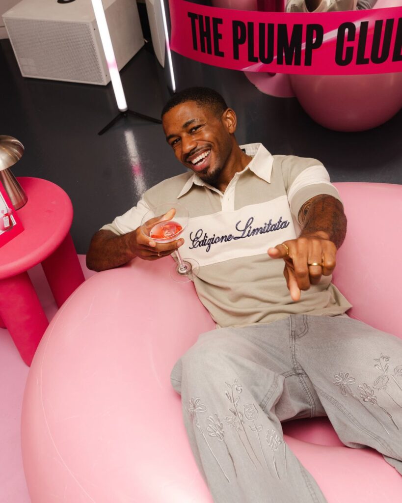 Guest seated on a pink inflatable at Kiehl’s Plump Club