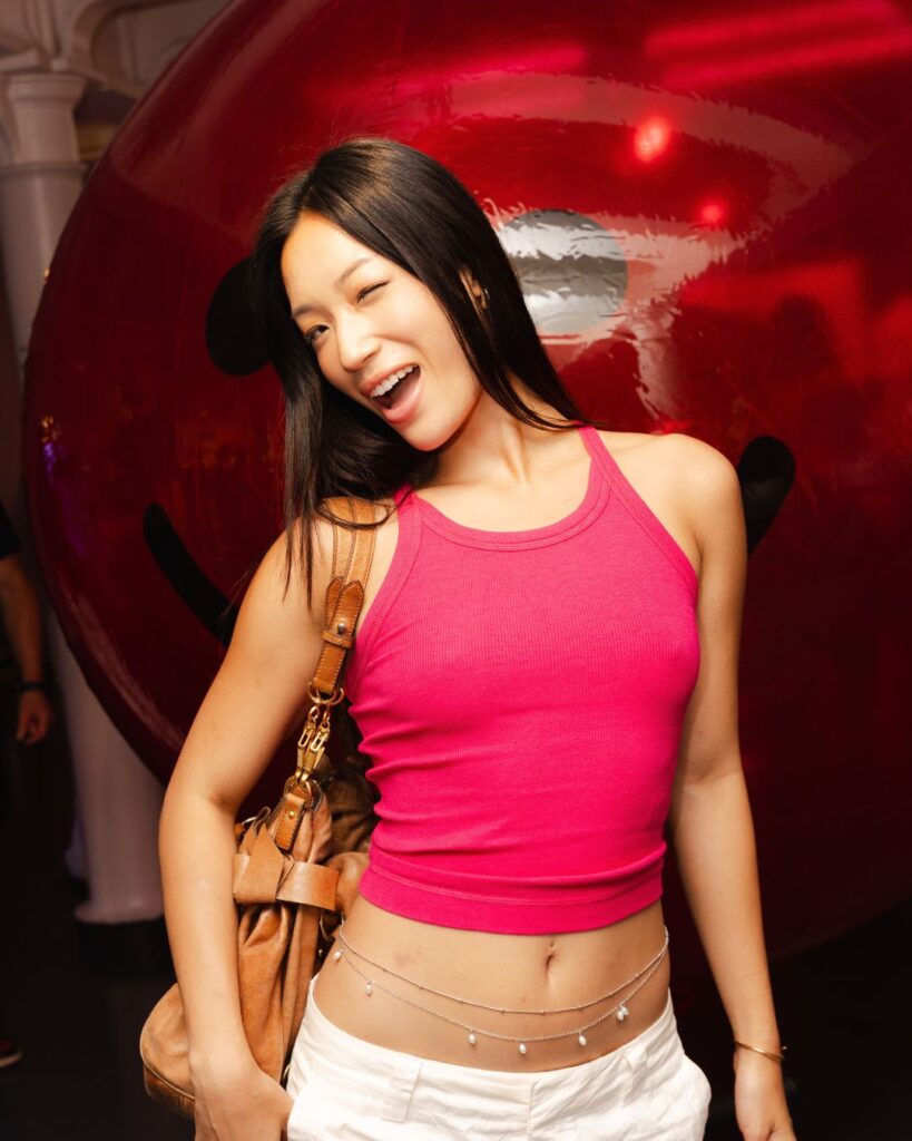 Guest posing in front of the oversized red balloon at Kiehl’s Plump Club