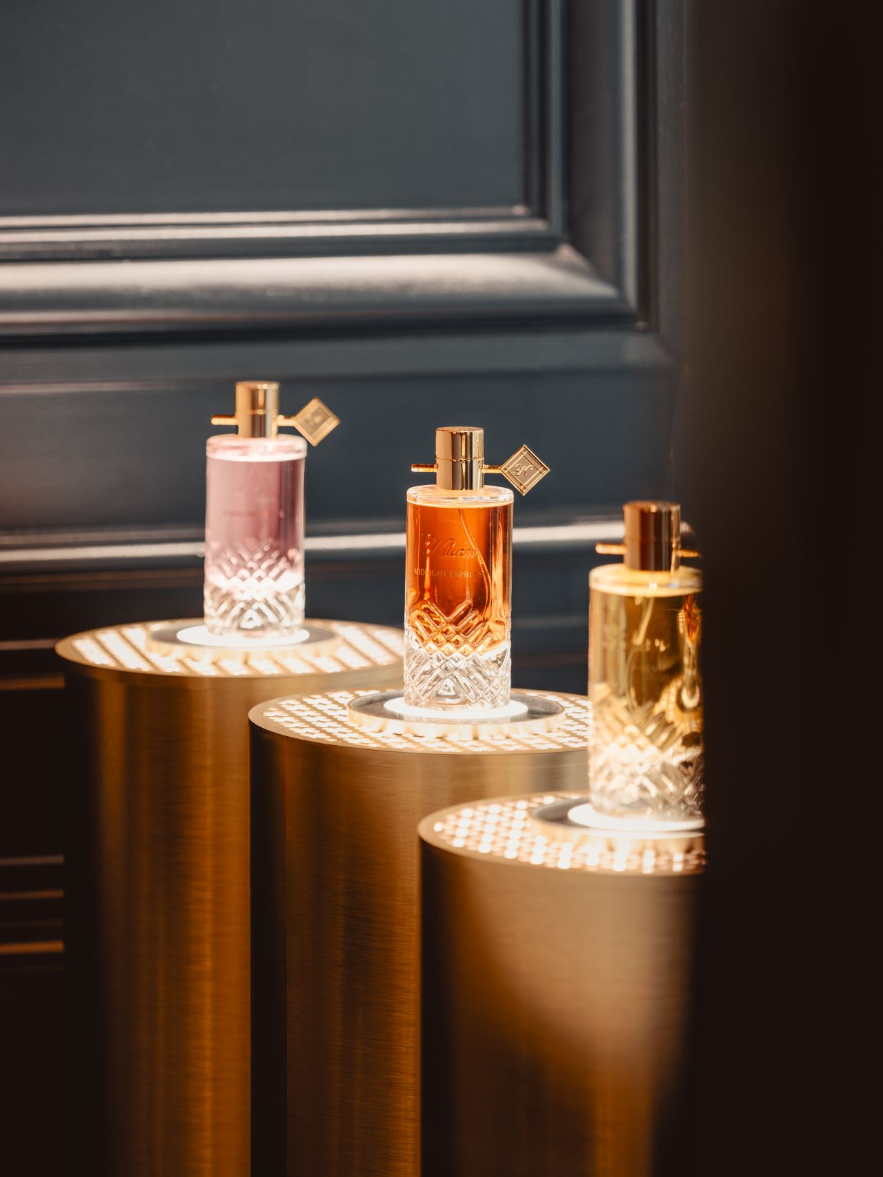 Three Kilian fragrance bottles on cylindrical display plinths