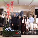 Guests at the Lacoste Godzilla launch beside character signage and a Godzilla figure