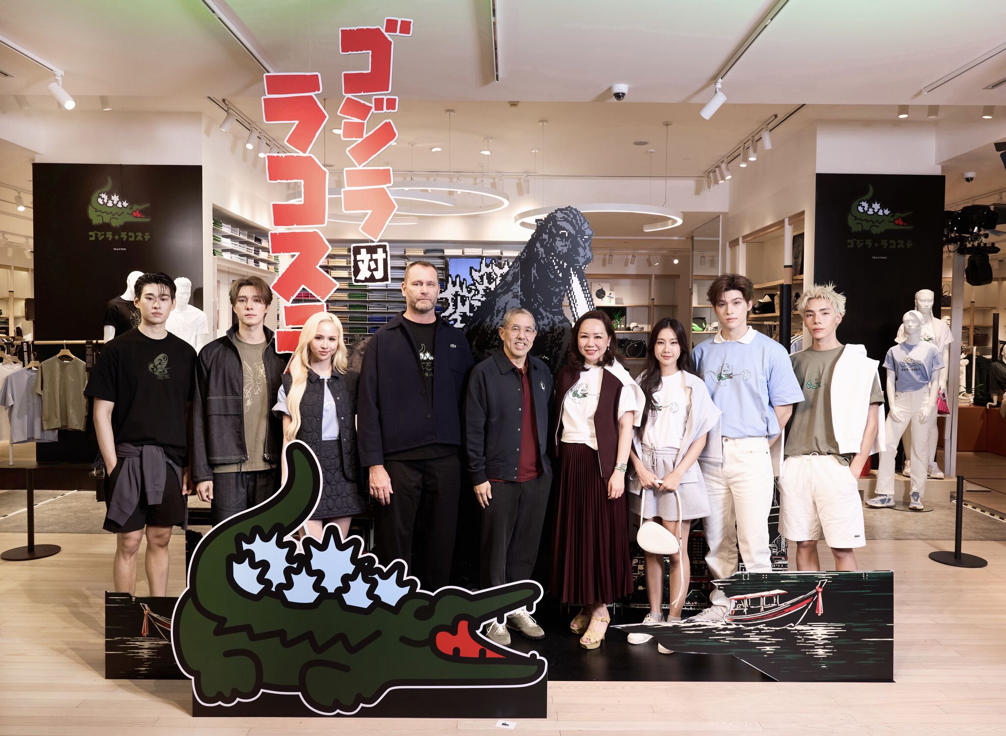 Guests at the Lacoste Godzilla launch beside character signage and a Godzilla figure