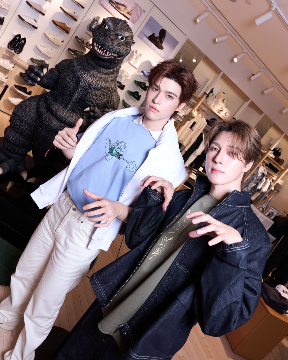 Two launch guests wearing Lacoste clothing beside a Godzilla figure
