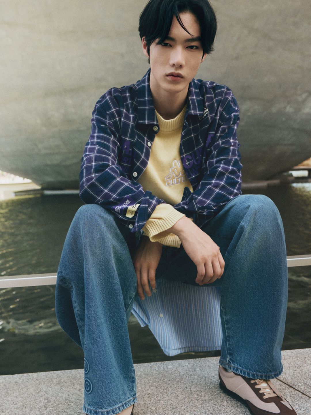 Model in checked overshirt, yellow knit and wide-leg jeans from Kappa Culture x Lefties